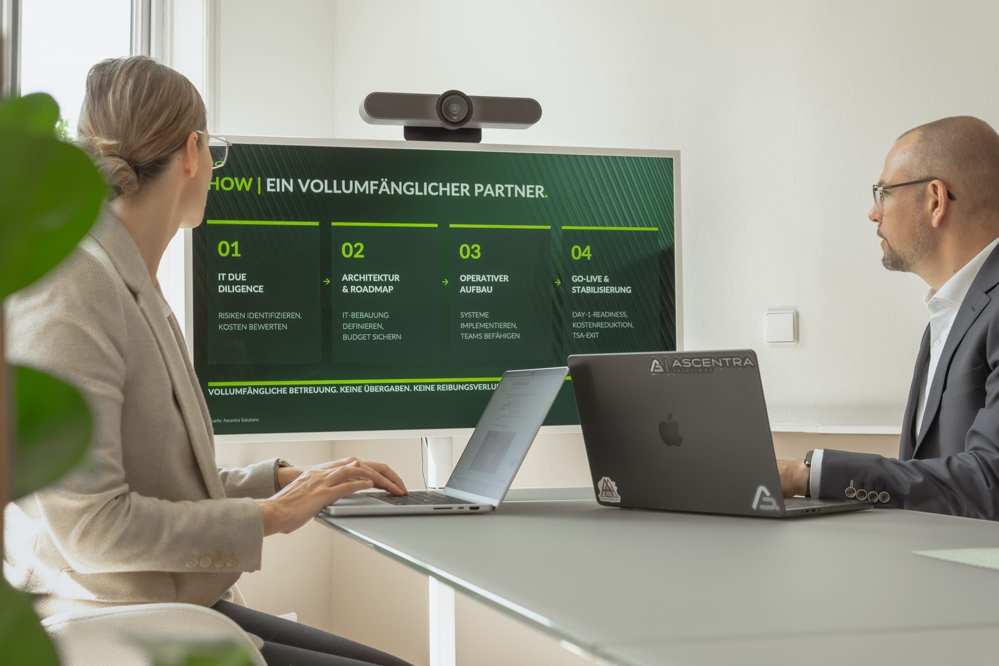 Michaela and Andreas Lippke discussing an Ascentra Solutions presentation on screen.